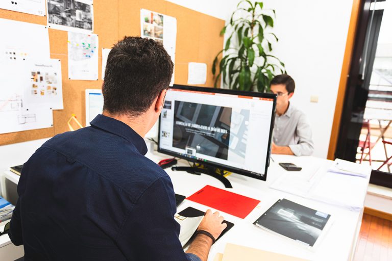 Trabalho em Portugal - Escritório com dois homens trabalhando na mesa e mexendo nos computadores
